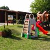 Un parco giochi con strutture per bambini su erba, tra cui uno scivolo rosso.