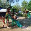 Bambini che giocano su uno scivolo verde in un parco giochi all'aperto.