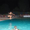 Una persona salta in aria sopra una piscina con spettatori seduti intorno di notte.