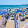 Spiaggia affollata con ombrelloni blu e gialli vicino al mare.